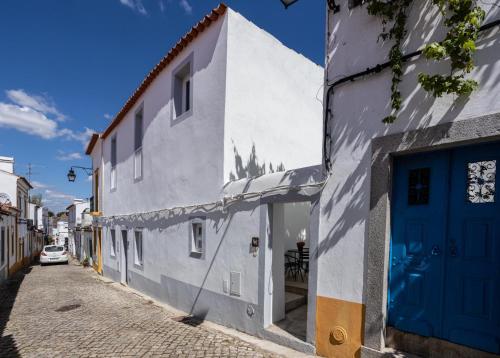 a white building with a blue door on a street at Alfar Story - Évora House in Évora