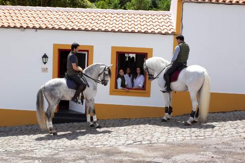 two people riding horses in front of a building at Quinta do Malhinha- Turismo in Angra do Heroísmo