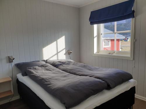 un letto in una camera da letto con finestra di Bensvik Brygge a Værøy