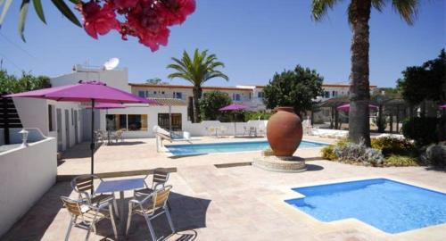 uma piscina com uma mesa e cadeiras e um guarda-sol em Centre Algarve em Moncarapacho