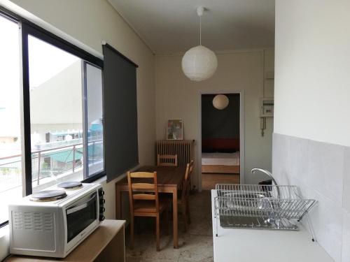 cocina con microondas y comedor con cama en 5th floor apartment with city view en Athens