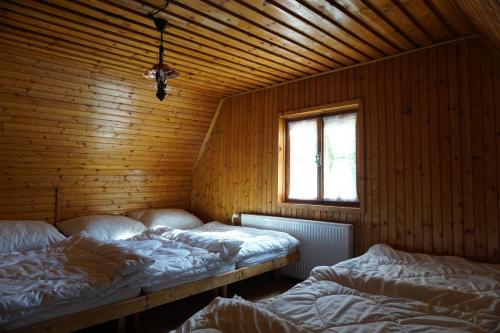 2 Betten in einem Zimmer mit einer Holzwand in der Unterkunft Chata Živa pod Babou horou in Oravská Polhora