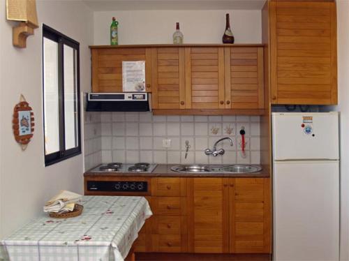 a kitchen with wooden cabinets and a white refrigerator at Apartamento las camelias 18 in Alaior