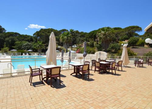a patio with tables and chairs next to a pool at Le Domaine de VILLEPEY By SdR in Fréjus