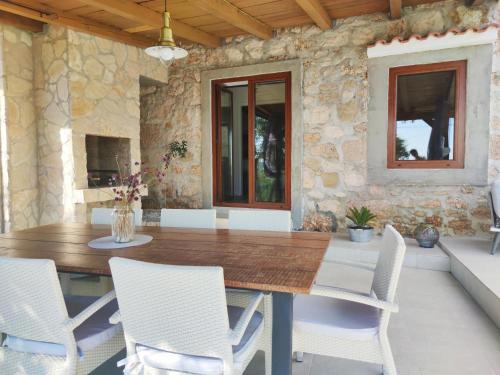 a dining room with a wooden table and white chairs at Stone hause Noa in Rab