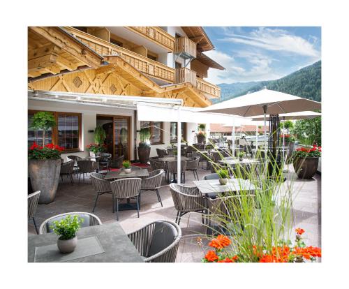 un restaurante al aire libre con mesas, sillas y sombrillas en Hotel Brugger, en Fulpmes
