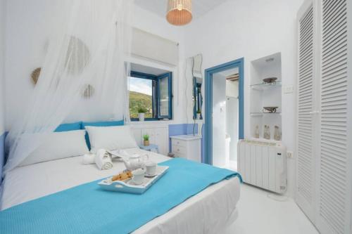 a white and blue bedroom with a tray of food on a bed at Apanemo in Kóronos
