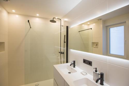 een badkamer met een wastafel en een glazen douche bij Ostend Seasight Luxury Apartment with free private parking in Oostende