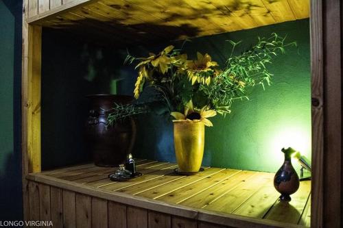 a vase filled with flowers on a wooden shelf at B&B al centro storico in Troina
