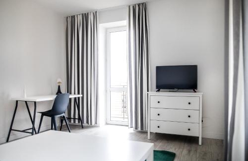 Apartament Nadbystrzycka no.01 في لوبلين: غرفة نوم بيضاء مع تلفزيون ومكتب ونافذة
