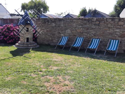 three chairs in a yard next to a stone wall at Longère briéronne 15 mn de La Baule in Saint-Lyphard