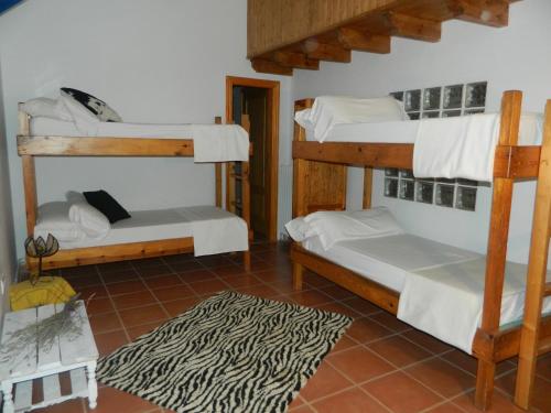 Habitación con 3 literas y alfombra. en El Cantalar, en Arroyo Frío