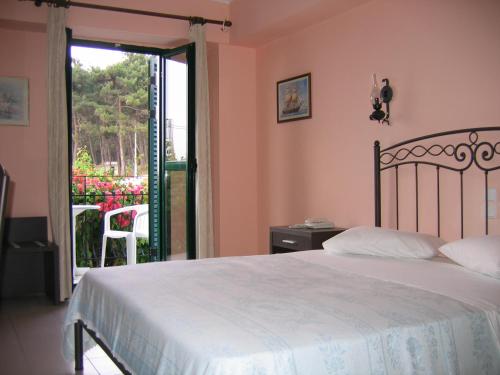 Schlafzimmer mit einem Bett und einer Tür zu einer Terrasse in der Unterkunft Tara Beach Hotel in Skala