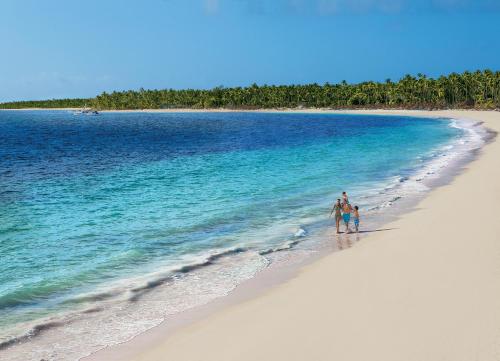 a person walking on the beach with a surfboard at Dreams Royal Beach Punta Cana in Punta Cana