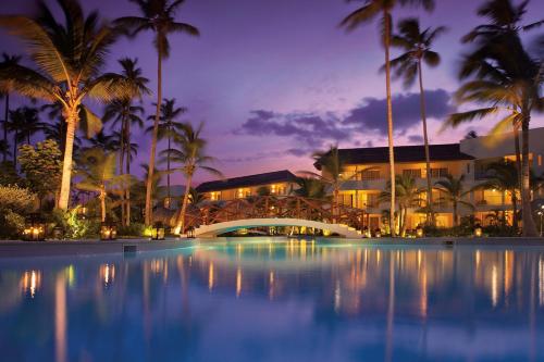 um resort com piscina e palmeiras à noite em Dreams Royal Beach Punta Cana - All Inclusive em Punta Cana