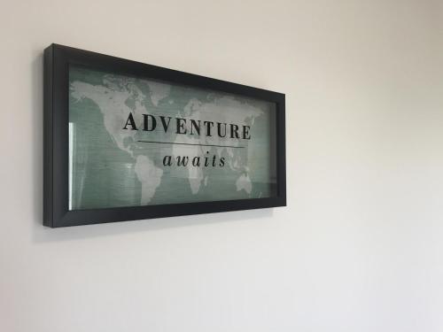 a framed picture of an adventure awaits on a wall at Apartman SONAS 2 with free private parking in Karlovac