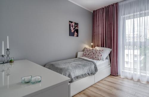 a white bedroom with a bed and a window at Flow Apartments Toruń in Toruń