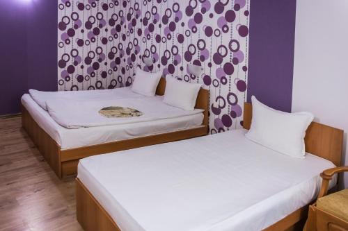 2 camas en una habitación con paredes moradas y blancas en къща Славяни, en Tryavna