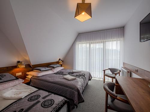 Habitación de hotel con 2 camas, mesa y sillas en Strama Kościelisko en Kościelisko