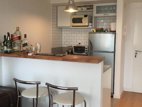 a kitchen with a counter with chairs and a refrigerator at Lo de Mario al rio in Buenos Aires