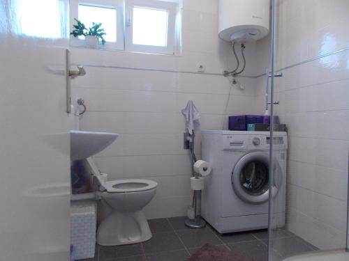 een badkamer met een toilet en een wasmachine bij Warm Terrace Apartments in Zadar