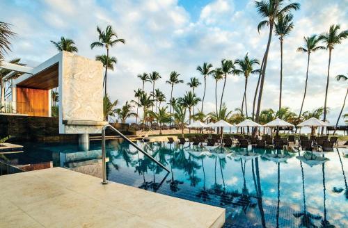 Secrets Royal Beach Punta Cana - Adults Only - All Inclusive في بونتا كانا: اطلالة المسبح في منتجع فيه نخيل