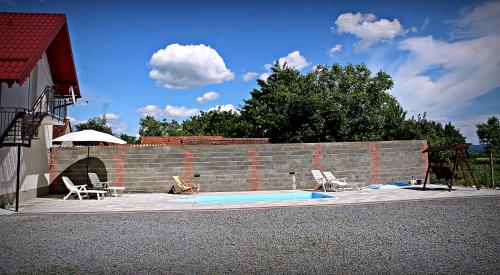 a swimming pool with chairs and an umbrella next to a brick wall at Yosefsfeld in Kutjevo