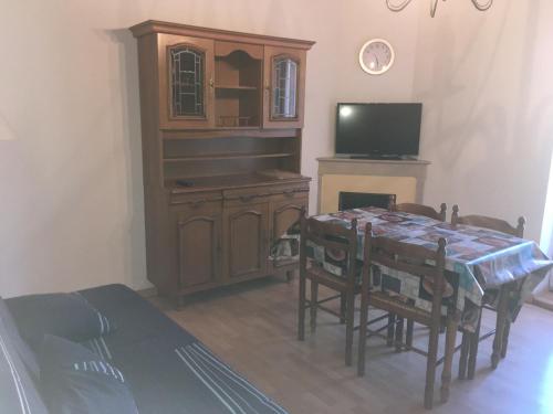 ein Esszimmer mit einem Tisch und einem TV in der Unterkunft Appartement au cœur du parc national des Cévennes in L'Espérou