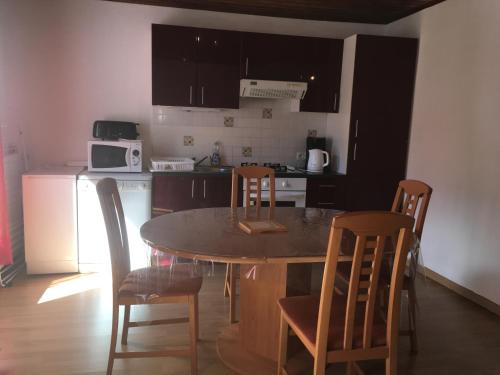 eine Küche mit einem Tisch und Stühlen sowie eine Küche mit einem Herd in der Unterkunft Appartement l'Espérou in L'Espérou