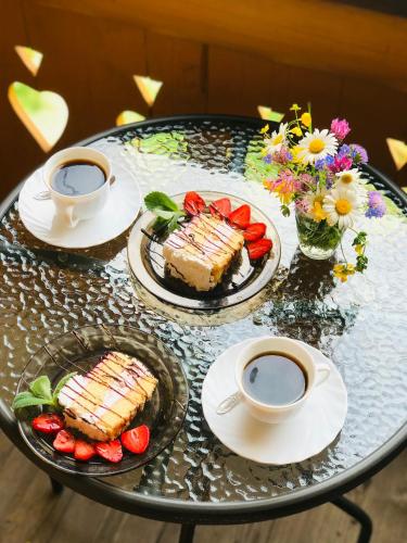 a table with two cups of coffee and cake and strawberries at SoloMia in Mykulychyn