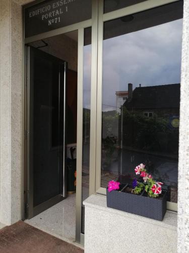 a window of a building with flowers in a box at Apartamentos MonteBlanco Costa da Morte in Neaño