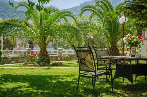 2 Stühle und ein Tisch im Garten mit Palmen in der Unterkunft San Giorgio Apartments in Skala Potamias