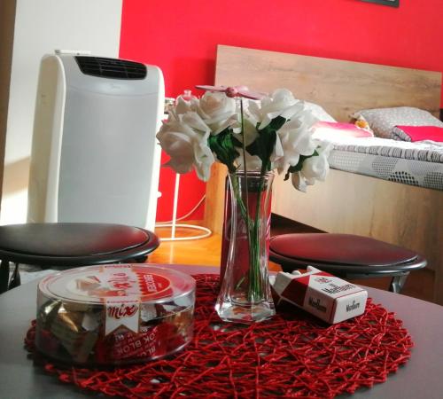 een tafel met een vaas met bloemen op een tafel bij Apartman Red wall in Čačak