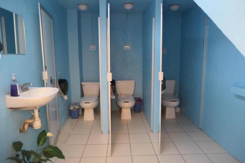 a blue bathroom with two toilets and a sink at Casa Kraken Hostel in Puerto Vallarta