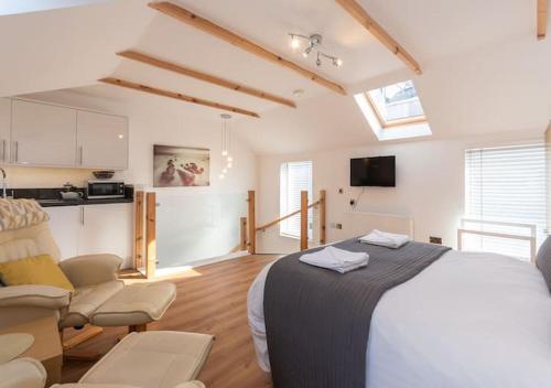 a bedroom with a bed and chairs and a kitchen at The Old Net Store - Cosy Anstruther Studio Flat in Cellardyke