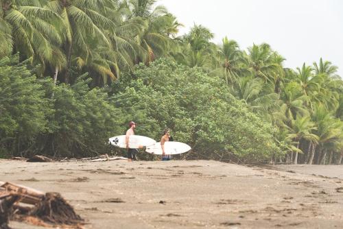 two men standing on a beach holding surfboards at El Vijo Surf in Nuquí