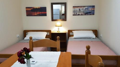 Cette chambre comprend 2 lits, une table et un miroir. dans l'établissement Fyllou Apartment Asprovalta, à Asprovalta