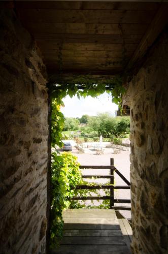a pathway through a stone wall with a gate at la ferme des epis in Ouffières