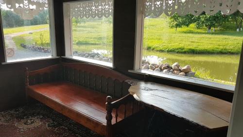 a bench in a room with two windows at GRAŽINOS SODYBA in Telšiai