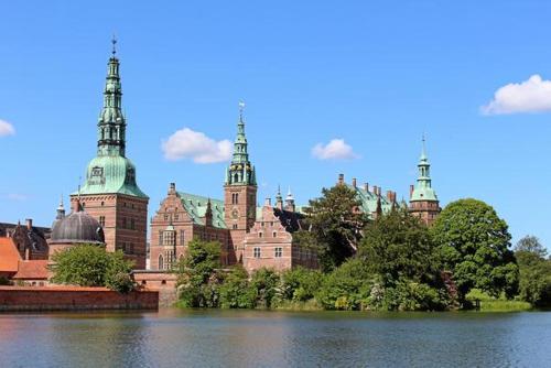 a large building with towers on the side of a lake at Mariegaardens Gæstehuse in Hillerød