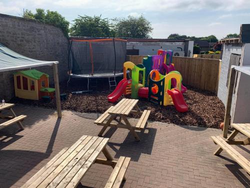 patio trasero con parque infantil con mesa de madera y bancos en The Carisbrooke, en Forres