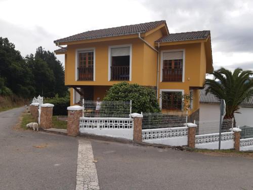 uma casa amarela com uma cerca branca em La estrella em Tineo