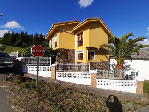 uma casa amarela com uma cerca branca e um sinal de stop em La estrella em Tineo