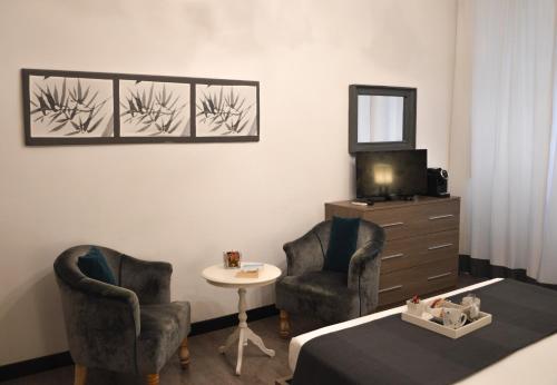 ローマにあるNobilcasa Suitesの椅子2脚、テーブル1台、鏡1台が備わる客室です。