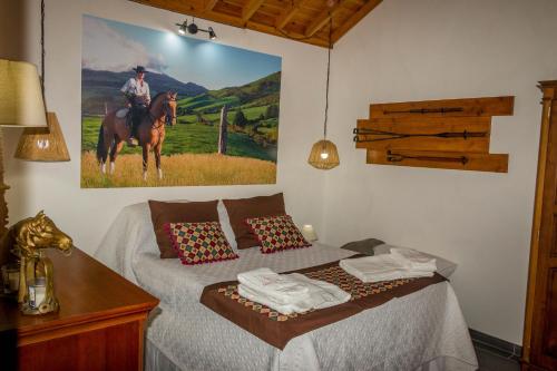 - une chambre avec un lit orné d'une peinture représentant un homme sur un cheval dans l'établissement Quinta do Malhinha- Turismo, à Angra do Heroísmo