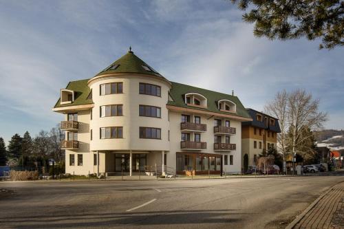 a large white building with a green roof at Apartmány Summit in Bešeňová