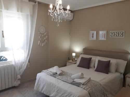 a bedroom with a bed with a chandelier and a window at Cute Home Bethlem in Cuenca