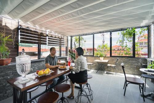 a man and woman sitting at a table on a patio at Narcissus Hotel & Apartment in Hanoi