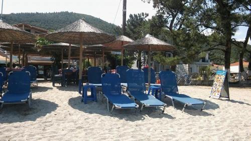 a group of blue chairs and umbrellas on the beach at Kohyli Apartments in Skala Rachoniou
