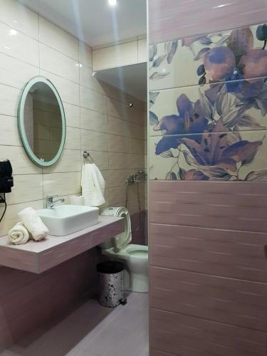 a bathroom with a sink and a toilet and a mirror at Kohyli Apartments in Skala Rachoniou